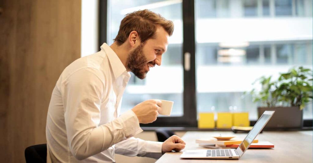 Man sitting in front of laptop while drinking coffee