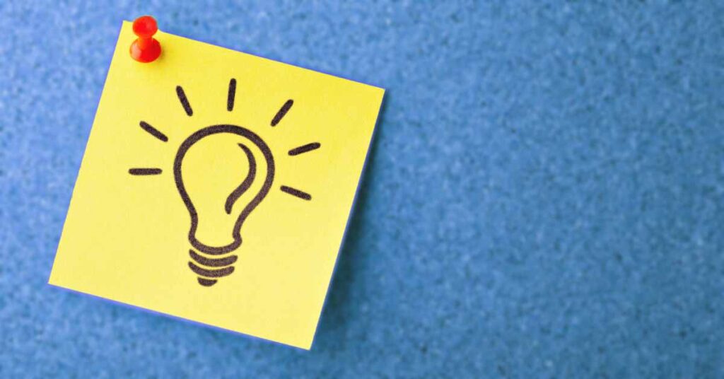 Sticky note with lightbulb on it pinned to board