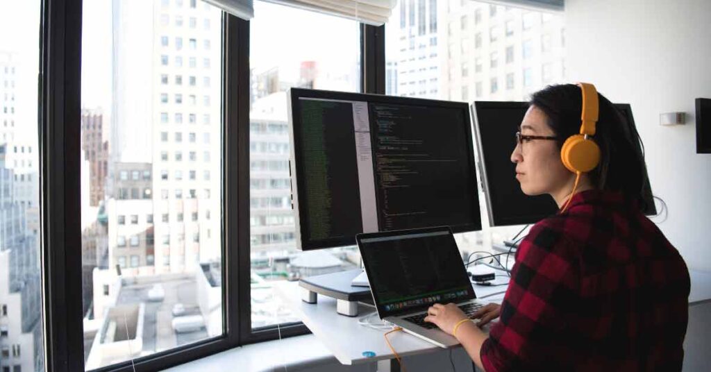 Web developer standing in front of workstation looking out of window