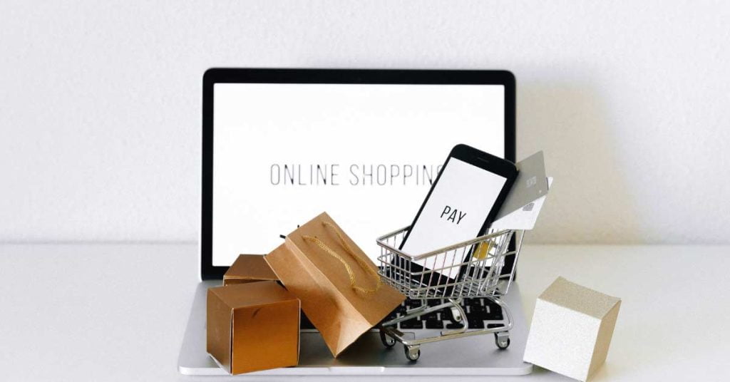 Image of shopping cart and bags on laptop representing online shopping